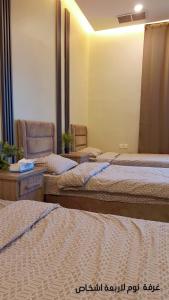 a room with three beds and a table and chairs at chalet B1 in Al Khīrān +25 photos