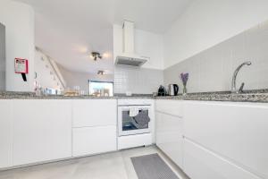 a white kitchen with granite counter tops and a sink at Casa Eva in Famara +28 photos