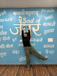 a woman is doing yoga in front of a blue wall at The Pink Nest - Backpackers Abode in Jaipur