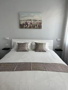 a large white bed in a bedroom with a painting on the wall at James Home in Quarto dʼAltino