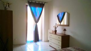 a bedroom with two windows and a dresser and a mirror at Sirolo Summer Appartamento in Sirolo