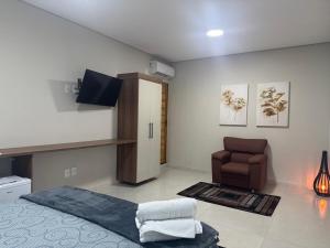 a living room with a bed and a chair at Pousada Avenida Farol in Campos dos Goytacazes
