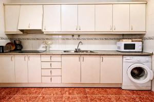a kitchen with white cabinets and a sink and a washing machine at Manomar II, tu refugio en Gata in Gata