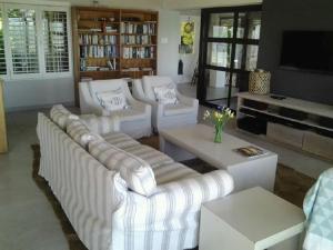 a living room with white couches and a tv at Dinvorae in Southbroom