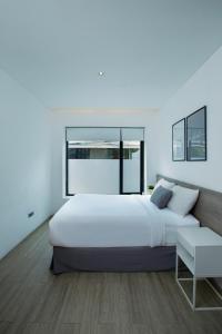 a white bedroom with a large bed and a chair at Ariama Serviced Residence in Jakarta