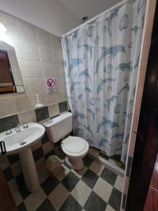 a bathroom with a toilet and a sink and a shower curtain at Complejo de departamentos 7 Cielos in Villa Carlos Paz +11 photos