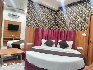 a hotel room with two beds and a tv at Hotel Sunlight in Ahmedabad