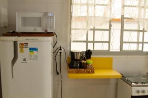 a kitchen with a white refrigerator and a microwave at Casinha Vale do Sol in Nova Lima