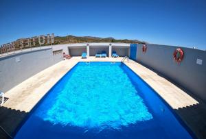 a swimming pool with blue water in a building at Hotel Beri in Llança