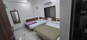 a small bedroom with two beds and a mirror at Hotel Shri Hari Har Inn in Godarpura