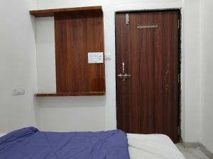 a room with a door and a bed and a mirror at Hotel Shri Hari Har Inn in Godarpura +1 photo