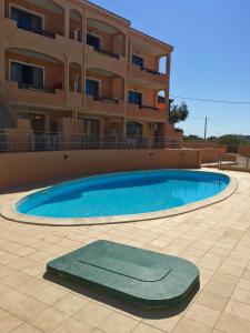 una grande piscina di fronte a un edificio di La Spiga Apartments a Castelsardo