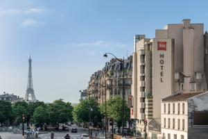 
a city street with tall buildings and a clock tower at Ibis Paris Gare Montparnasse 15ème in Paris
