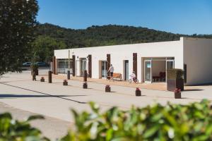 a white building with people on a sidewalk at Camping Ridaura in Llagostera