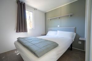 a bedroom with a large bed with white sheets and a window at Camping Ridaura in Llagostera