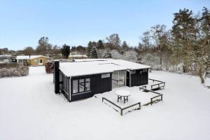 a black cabin with a table in the snow at LL267-Tranekaer-Bellisvej-2 in Stoense