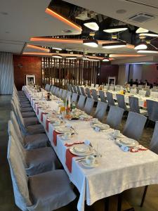 a long table with white tables and chairs in a room at Hotel Cztery Korony in Śrem