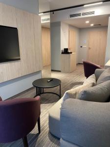 a living room with a couch and a tv at Hotel Cztery Korony in Śrem