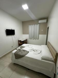 a bedroom with a large white bed and a television at Pousada Salomão in Teixeira de Freitas