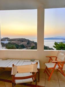 a room with a table and chairs and a large window at Lime Andros Maisonette by HOSTANDROS in Apróvaton