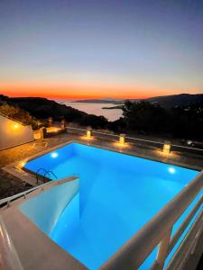 a swimming pool with a view of the ocean at sunset at Lime Andros Maisonette by HOSTANDROS in Apróvaton +14 photos