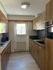 an empty kitchen with wooden cabinets and a window at Salü 5 in Saas-Fee