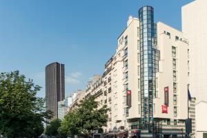 a tall white building in a city with tall buildings at Ibis Paris Gare Montparnasse 15ème in Paris
