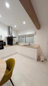 a kitchen with white cabinets and a table and a chair at Chez Lucia petite maison a la campagne pour 4 pers ,parking prive in Istres
