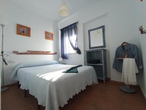 a white bedroom with a bed and a window at BOL16 in Bolonia