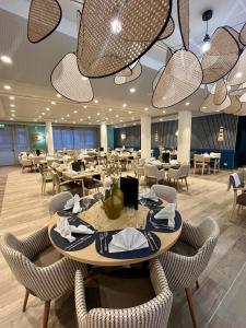 a dining room with tables and chairs and chandeliers at DOMITYS - L'Elyme des sables in Neufchâtel-Hardelot