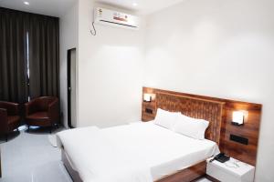 a bedroom with a large white bed and a chair at Emerald Nest in Pandharpur