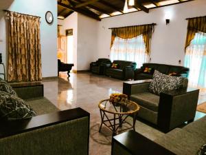 a living room with couches and chairs and a clock at Wellassa Hillside Villa in Kendagolla