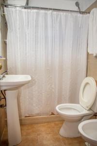 a bathroom with a white shower curtain and a toilet at Apart Hotel Manantiales Termal in Termas del Daymán +24 photos