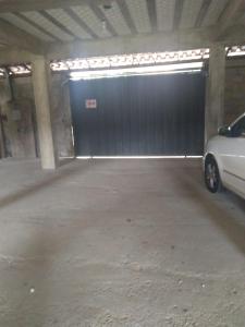 a garage with a black garage door with a car parked in it at Maxi conforto e vista para o Itacolomi in Ouro Preto