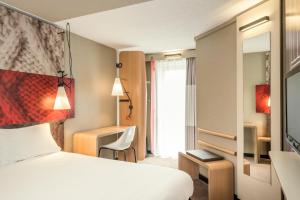 パリにあるIbis Paris Gare Montparnasse 15èmeのベッドと窓が備わるホテルルーム
