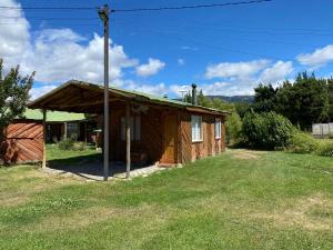 a small wooden cabin with a grass yard at Patagonia Bordelago Lodge in Puerto Ingeniero Ibáñez