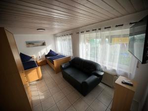 a living room with a black leather chair and a couch at Familie-Ising aus de in Unterwörnitz +3 photos