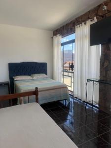 a bedroom with two beds and a balcony with a television at Pousada Ju Haus in Navegantes