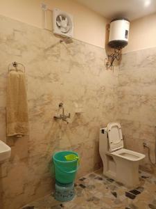 a bathroom with a toilet and a green bucket at Chill with pahadi in Lansdowne