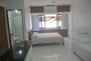 um pequeno quarto com uma cama e uma janela em Estúdio Ibiza II em Maceió