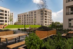 a garden with benches and tables in front of buildings at apartman Sole in Trnava