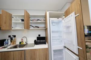 a refrigerator with its door open next to a sink at Modern Waterfront Studio | Steps from Cleveland Clinic in Abu Dhabi