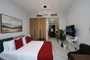 a bedroom with a large white bed with red pillows at Modern Waterfront Studio | Steps from Cleveland Clinic in Abu Dhabi