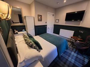 a hotel room with a bed and a television at The Original Rosslyn Inn in Roslin