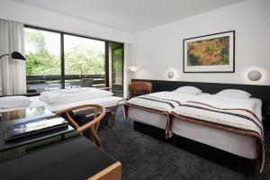 a hotel room with two beds and a desk at Munkebjerg Hotel in Vejle