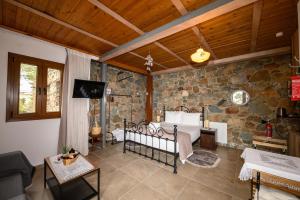 a bedroom with a bed and a stone wall at Fikardou Chalets in Phikardhou