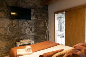 a bedroom with a bed and a tv on a stone wall at Bellu Suites by GuestPro in Guimarães