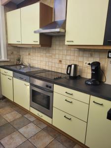eine Küche mit weißen Schränken und einem Herd mit Backofen in der Unterkunft Flo house in Diksmuide