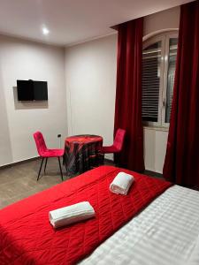 ein Schlafzimmer mit einem roten Bett, einem Tisch und Stühlen in der Unterkunft Hotel Iris in Varcaturo