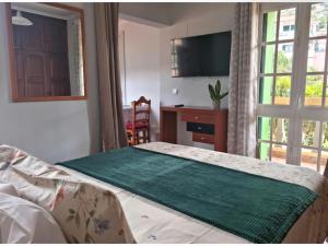 a bedroom with a bed and a desk and a window at Studio em Machico in Machico